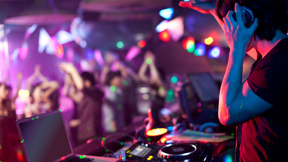 DJ legt Musik in einem Club auf und Menschen tanzen.