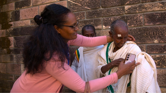 Bahritu Seyoum hilft einer Frau, eine Weste anzuziehen.