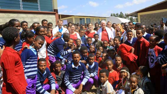 Eine Gruppe von Schulkindern und Lehrenden in traditionellen Gewändern steht vor der neu errichteten Schule in Ginchi.