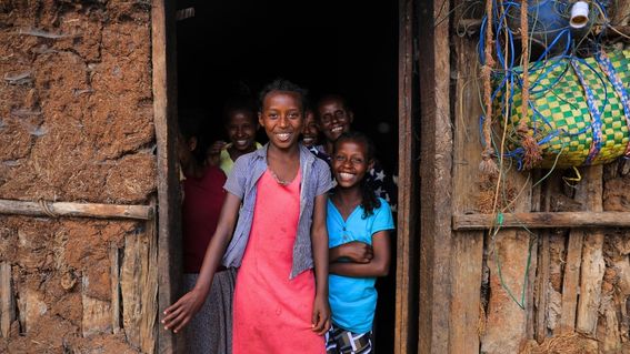 Eine Gruppe aus jüngeren und älteren Menschen steht im Hauseingang und lächelt in die Kamera.