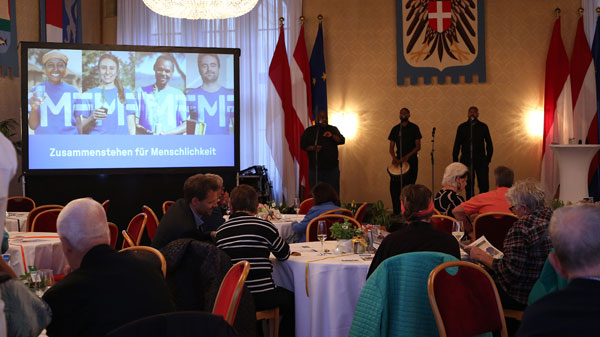 Fotoaufnahme des Veranstaltungsraumes im Wiener Rathaus mit Gästen an runden Tischen.