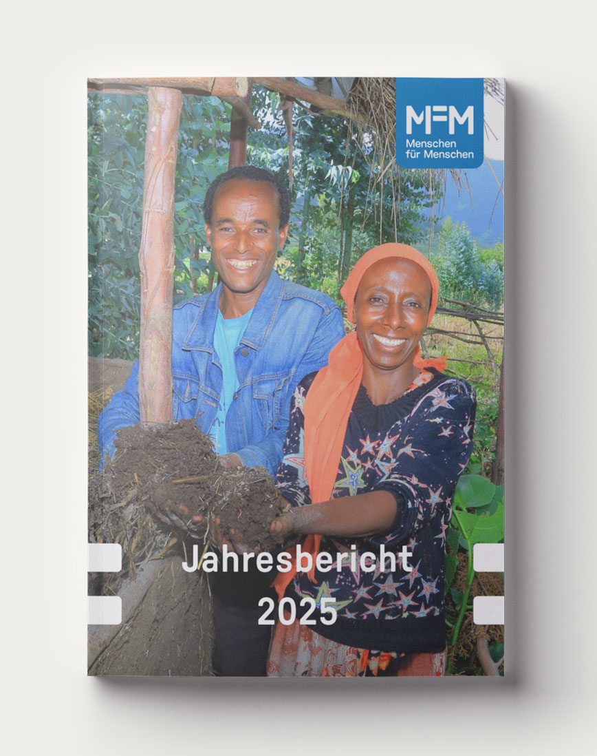 Das Titelbild des Jahresberichts 2025 zeigt eine Frau und einen Mann, die in ihrem Garten frische Erde aus einem Wurmbeet entnehmen.