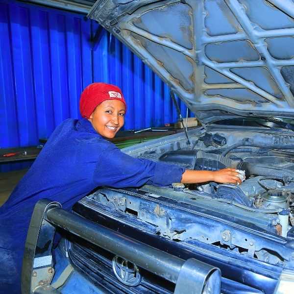 Eine Mechanikerin repariert ein Fahrzeug.