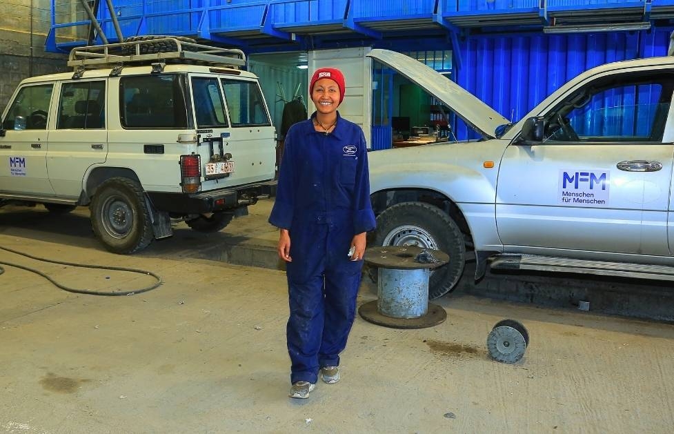 Eine Mechanikerin steht in der Werkstatt des Projektkoordinationsbüros in Addis Abeba; im Hintergrund sind die Fahrzeuge zu sehen, die repariert werden müssen.