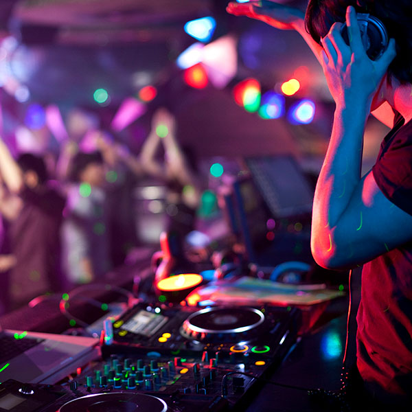 DJ legt Musik in einem Club auf und Menschen tanzen.