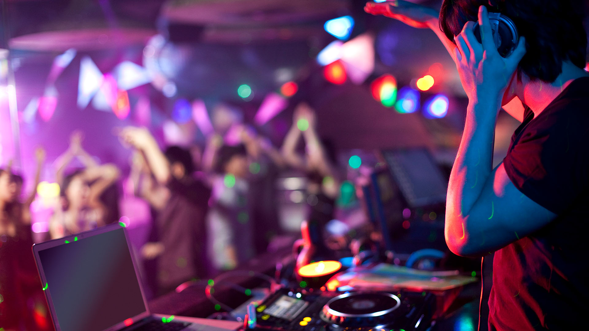 DJ legt Musik in einem Club auf und Menschen tanzen.