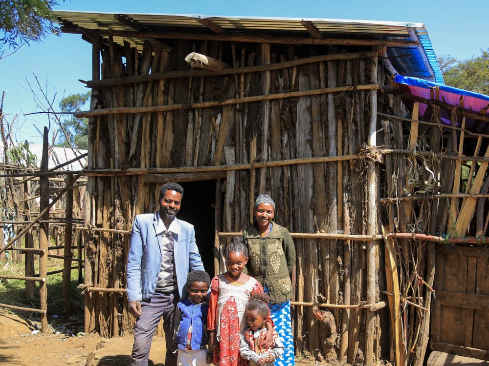 Äthiopische Familie vor neuem Holzhäuschen mit Blechdach