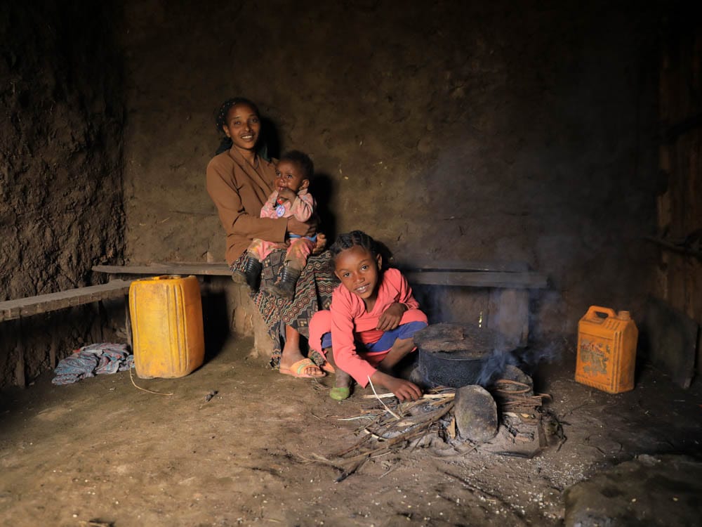 Mutter mit ihren Kindern in dunkler äthiopischer Küche bei offenem Feuer
