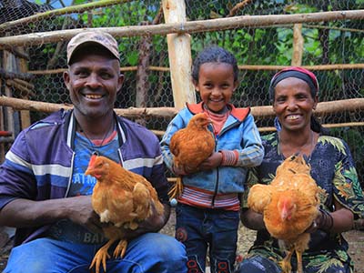 Äthiopische Familie hält ihre Hühner in den Händen und lächelt erfreut.