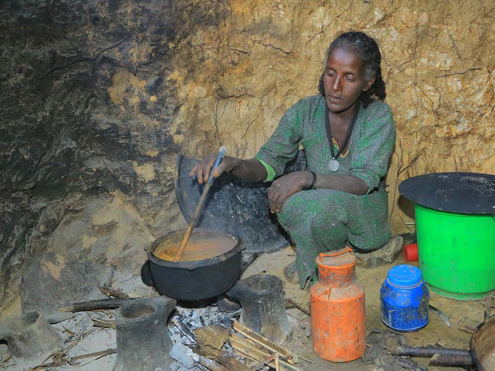 Eine äthiopische Frau kocht Soße in einem Topf über offenem Feuer