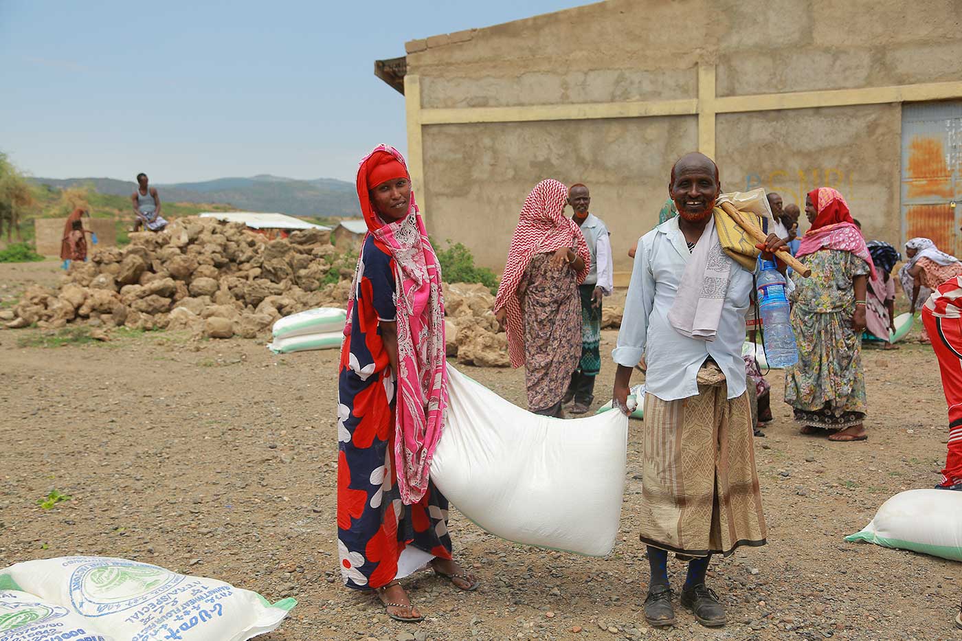 Eine Frau und ein Mann bei einer Nahrungsmittelausgabe in Äthiopien tragen einen Sack Getreide 