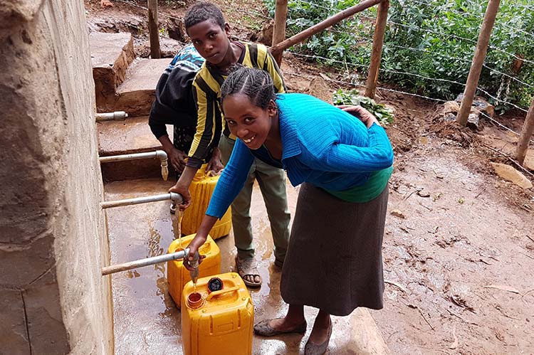 Mädchen und Jungen in Äthiopien holen Wasser aus einer Menschen für menschen Quelle