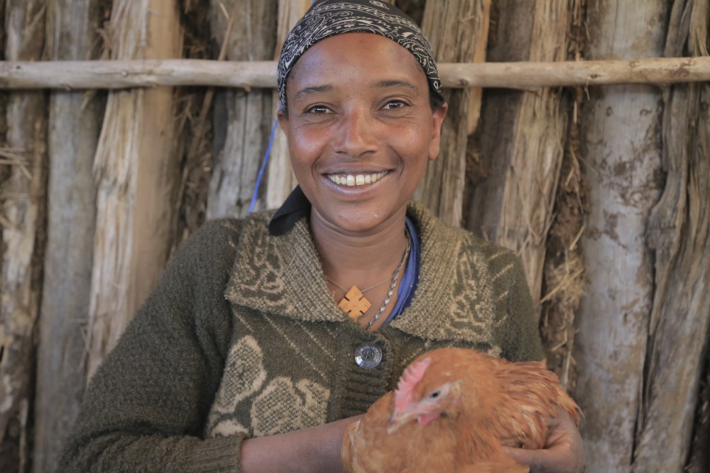 Eine glückliche äthiopische Frau hält ihre Henne in den Händen