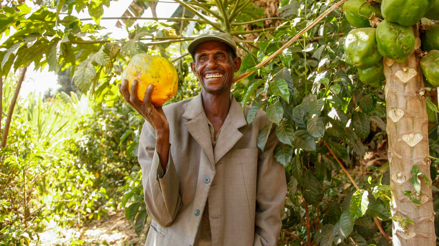 Lächelnder Mann in Äthiopien mit Papaya in der Hand