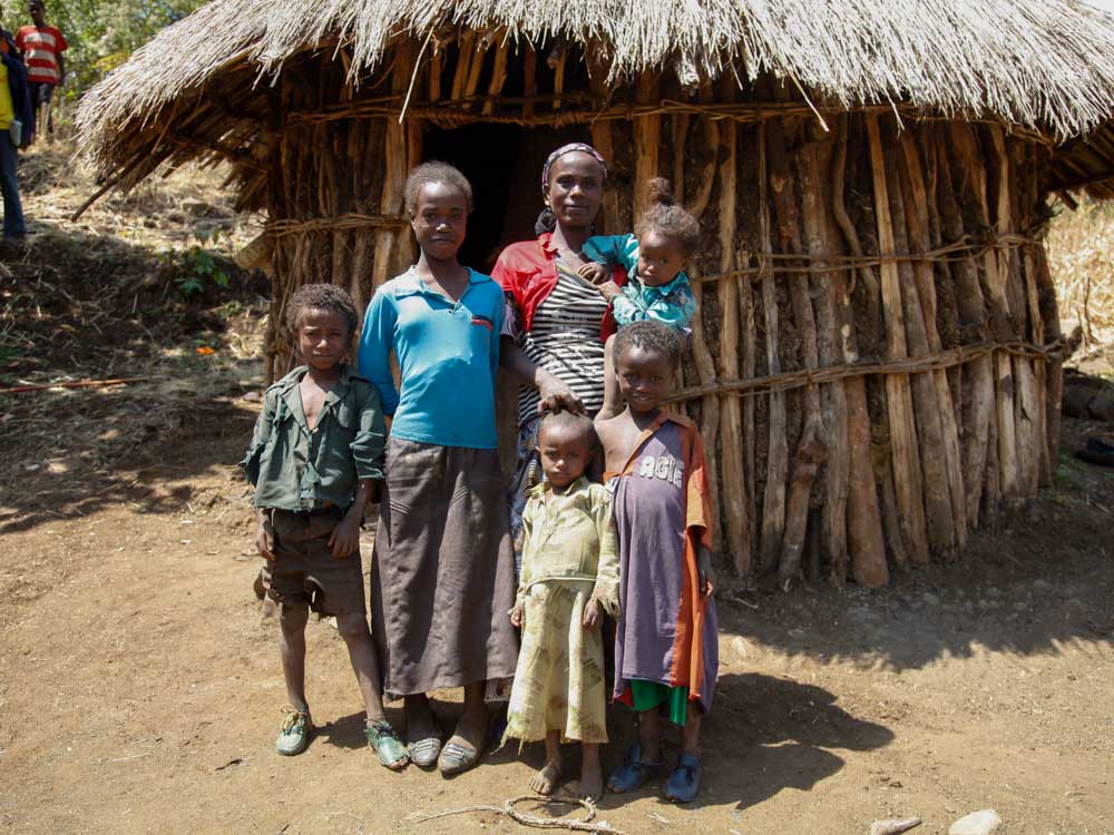 Familie mit fünf Kindern steht vor Holzhütte in Äthiopien