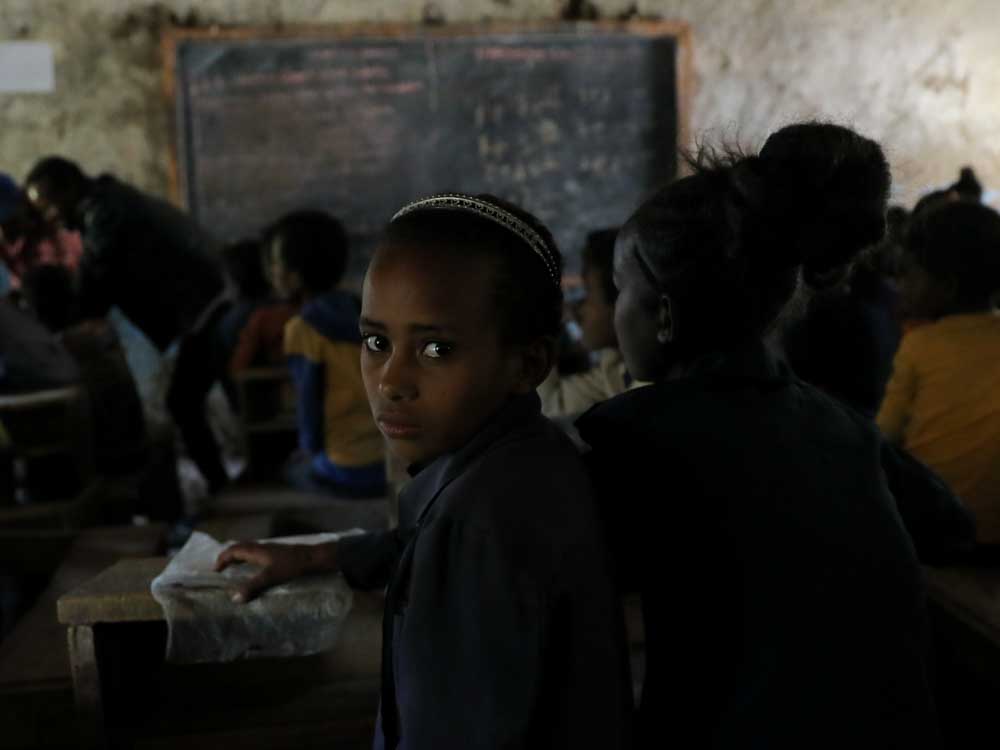 Schülerin in dunkler baufälliger Schule in Äthiopien blickt in die Kamera