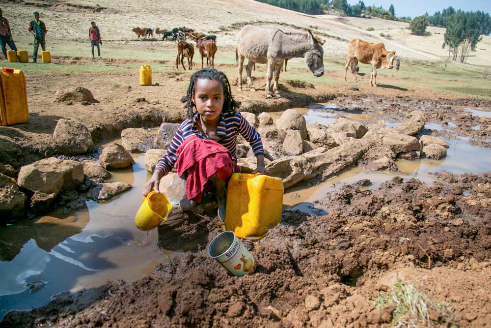 Mädchen in Äthiopien holt Trinkwasser aus einer dreckigen Pfütze