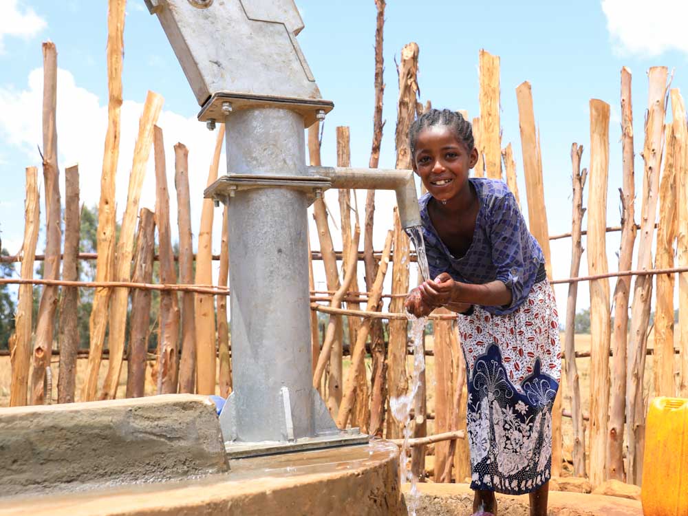 Mädchen in Äthiopien holt sauberes Trinkwasser aus einem Brunnen von Menschen für Menschen