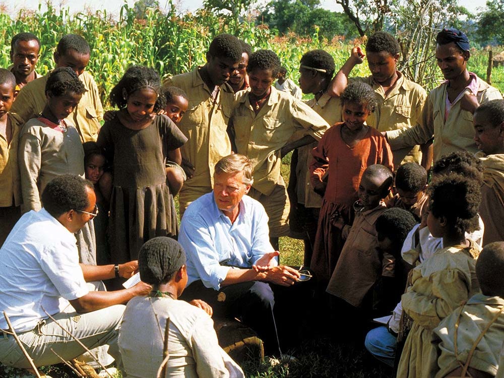 Berhanu Negussie und Karlheinz Böhm sitzen in einer Menschengruppe.