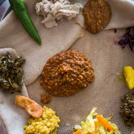 Injera, Sauerteigfladen aus Teff, mit unterschiedlichen Eintoepfen.