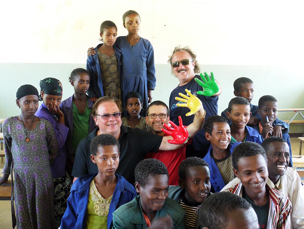 Mitglieder von Opus mit bunt angemalten Händen umringt von äthiopischen Kindern